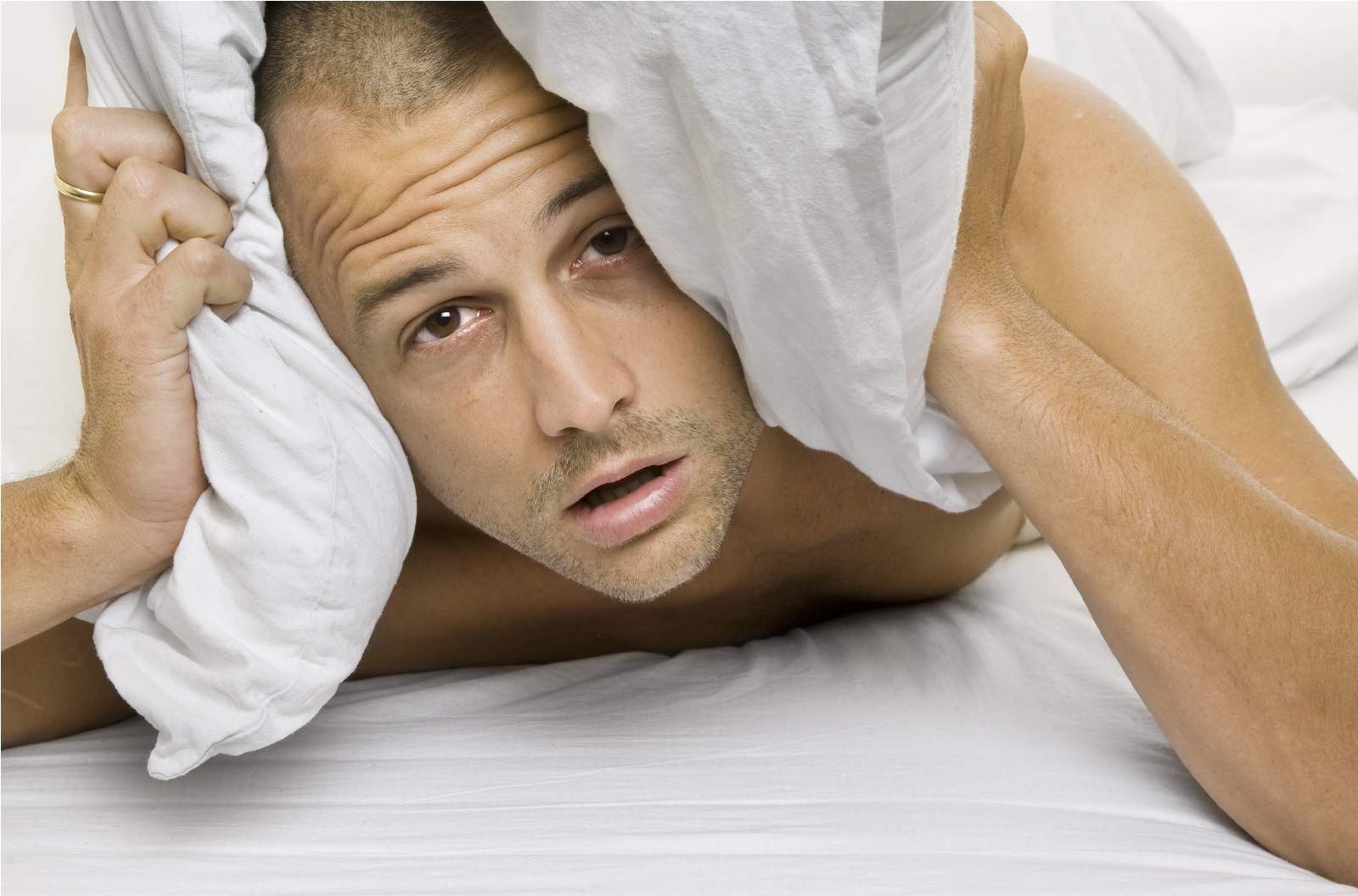 Man trying to sleep with a pillow over his head