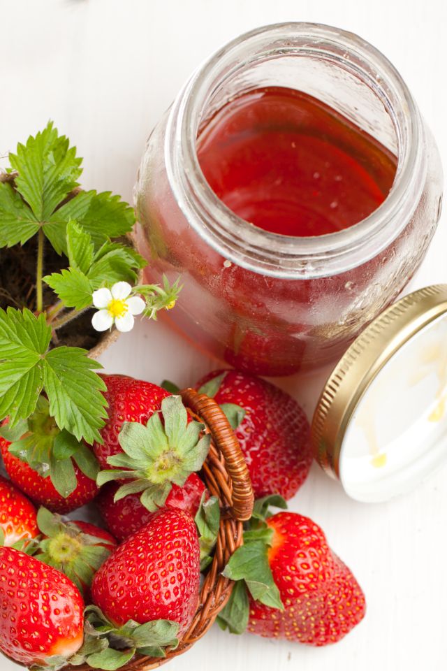Basker of fresh strawberries and pot of honey