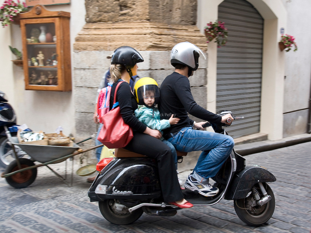 Mother, father and child riding a Vespa motorscooter, Corso Ruggero, Cefalu, Sicily, Italy