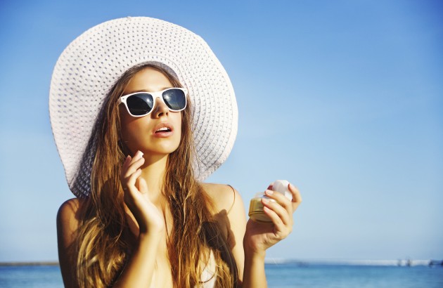 Woman-in-wide-brimmed-hat-and-sunglasses-applying-sunscreen-at-beach-186957862-Credit-iStock-630x410