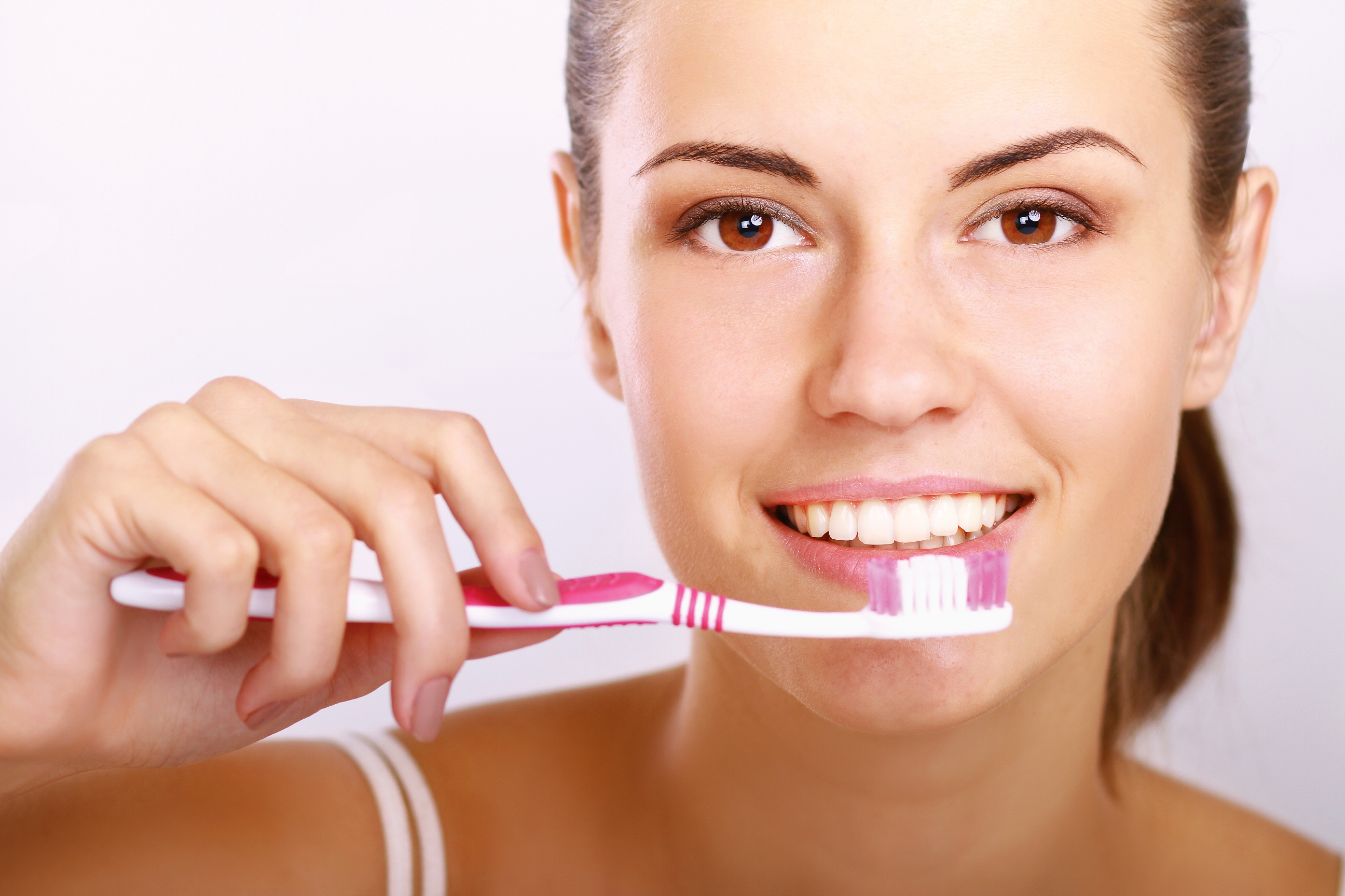 Woman with great teeth holding tooth-brush, isolated on white background